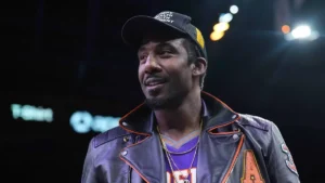 Amar'e Stoudemire en veste de cuir et casquette au bord d'un terrain de NBA