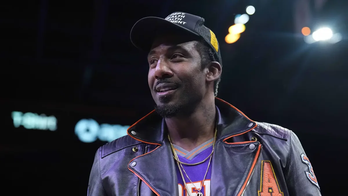Amar'e Stoudemire en veste de cuir et casquette au bord d'un terrain de NBA
