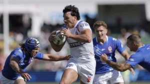 Un joueur anglais ballon en main face à trois défenseurs français, Coupe du monde de rugby à XIII à Perth, octobre 2026