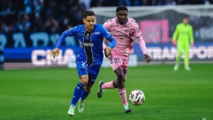 Un joueur d'Auxerre file balle au pied devant un Havrais en rose au stade Océane, le 18 octobre 2026