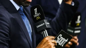 Micro Canal+ aux couleurs de la Ligue 1 tenu par un consultant au bord d'un terrain