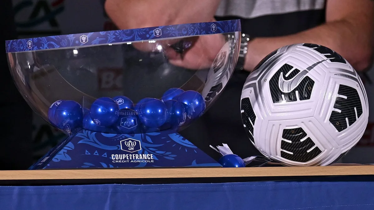 Urne et boules du tirage au sort de la Coupe de France à côté d'un ballon de match