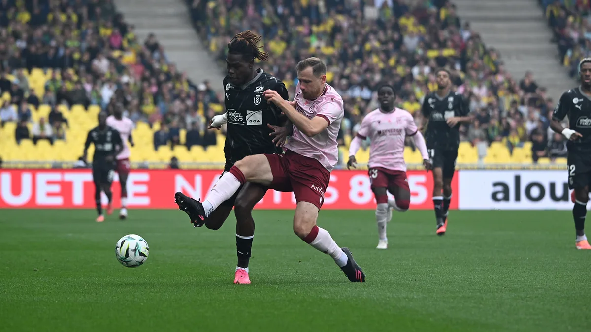 Un Nantais en maillot rose au duel avec un Rémois à la Beaujoire, lors de Nantes-Reims le 10 octobre 2026
