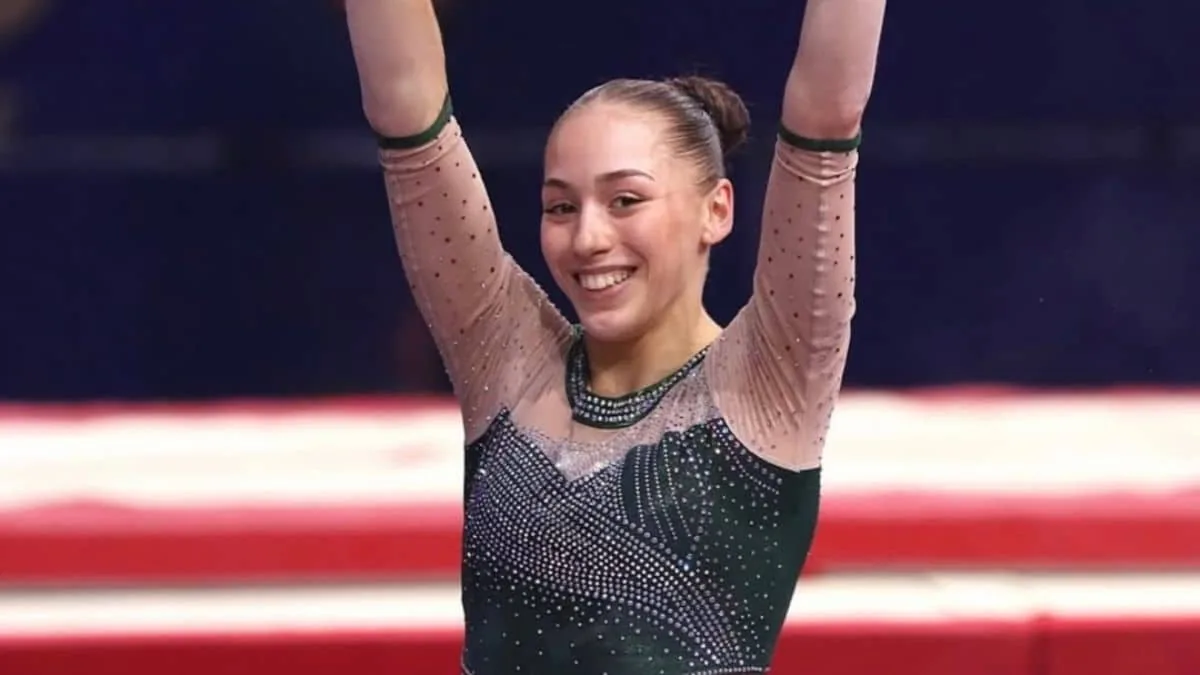 Kaylia Nemour, bras levés et souriante, en justaucorps de l'équipe d'Algérie lors d'une compétition