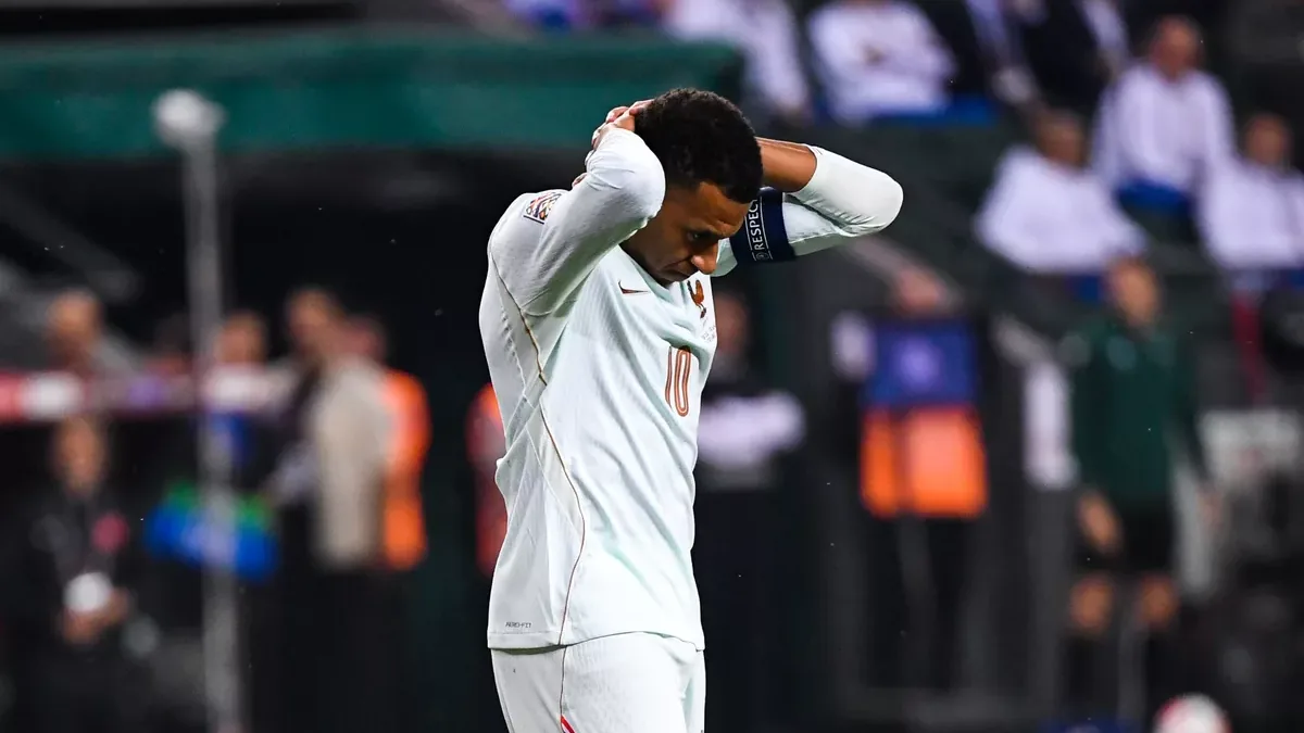 Kylian Mbappé, brassard de capitaine, les mains sur la tête sous le maillot blanc de l'équipe de France