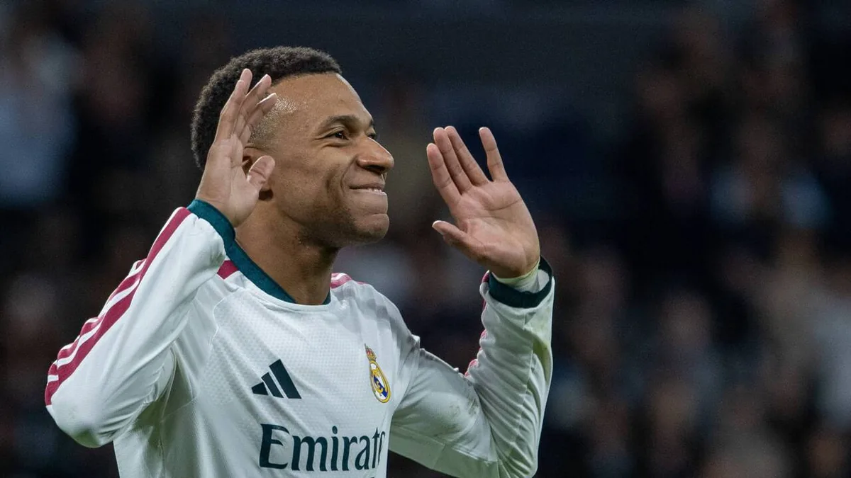 Kylian Mbappé, mains levées, sous le maillot blanc du Real Madrid pendant un match