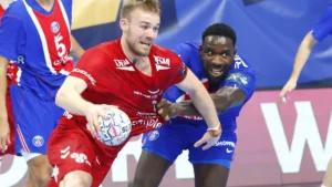 Un joueur d'Aalborg ballon en main face à un défenseur du PSG à Coubertin en Ligue des champions, octobre 2026
