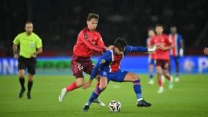 Tyler Morton sous le maillot de l'OL au duel avec un Parisien au Parc des Princes, octobre 2026