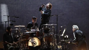 Bono au micro, entouré des musiciens de U2, sur scène lors d'un concert du groupe irlandais