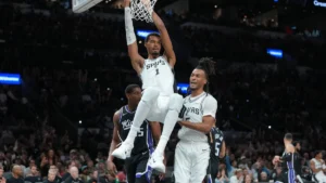 Victor Wembanyama accroché au cercle après un dunk avec les Spurs face aux Sacramento Kings, octobre 2026